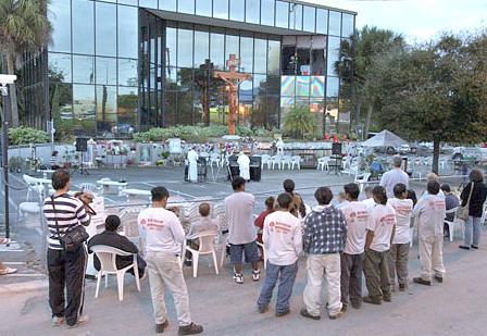 A crowd gathers Monday evening at the Shepherds of Christ Ministries building in Clearwater for a prayer service in front of the broken glass panels.